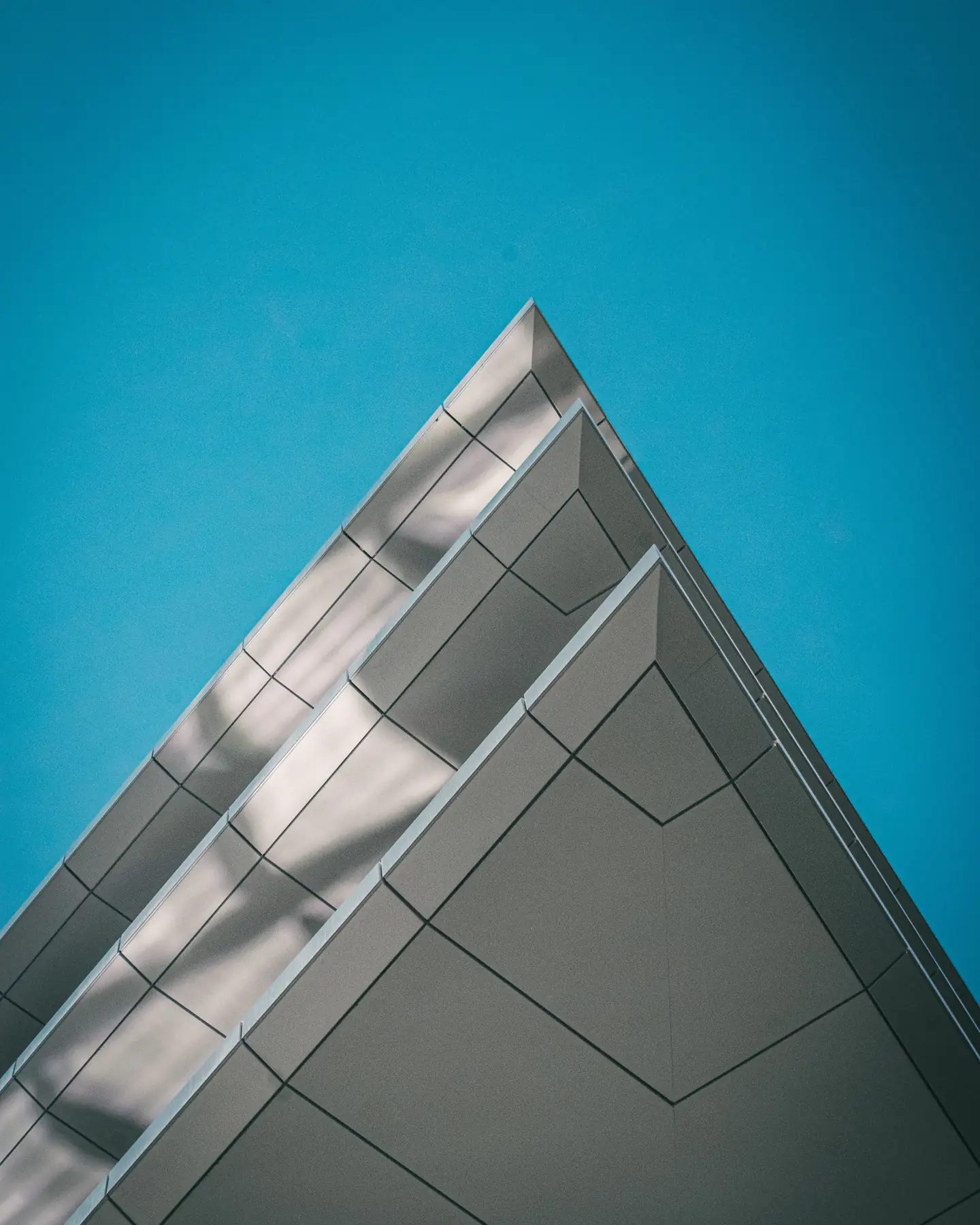 The corner of a modern building rising against a teal sky