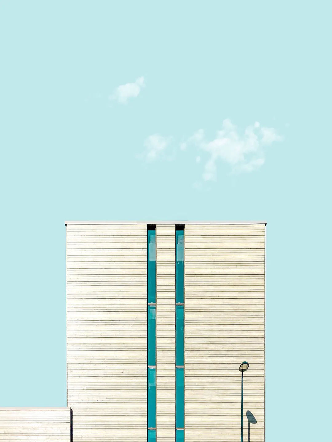 A pale European building with teal glazing under an open sky